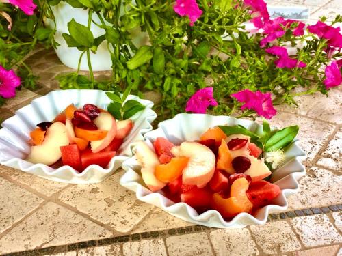two paper plates of fruit on a table with flowers at Villa Franci in Santa Teresa Gallura