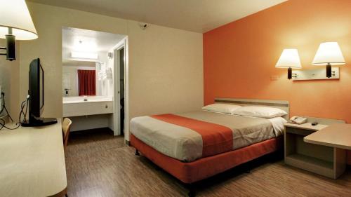 a hotel room with a bed and a television at Super 8 by Wyndham Woods Cross - Salt Lake City North in Woods Cross