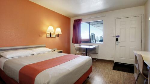 a hotel room with a bed and a desk and a window at Super 8 by Wyndham Woods Cross - Salt Lake City North in Woods Cross