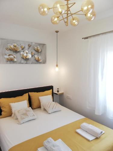 a bedroom with a bed with white sheets and a chandelier at Olive Tree - House with Pool in Vinišće