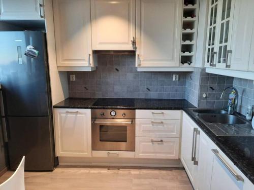 a kitchen with white cabinets and a stainless steel refrigerator at Nydelig leilighet, Free parking near sentrum in Bergen