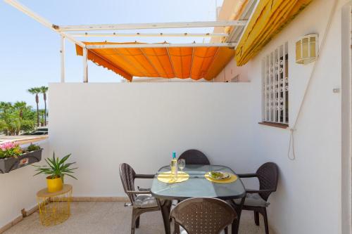 a table and chairs on a patio with an orange roof at Right on the beach in Benalmádena