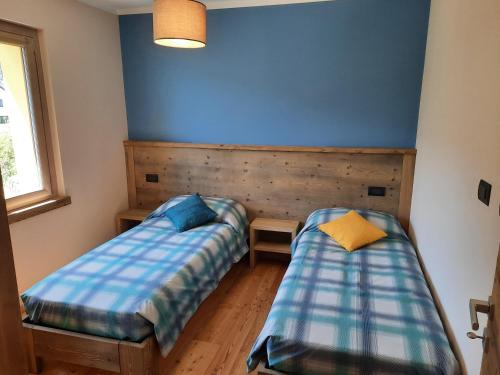 two beds in a room with a blue wall at CasAmici in Bognanco