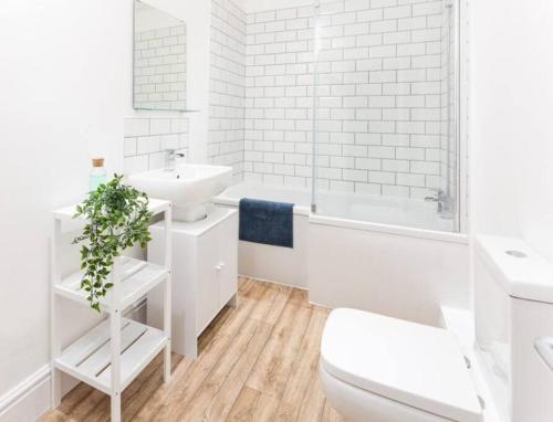 a white bathroom with a tub sink and a toilet at Spaces by Hexagon in Liverpool
