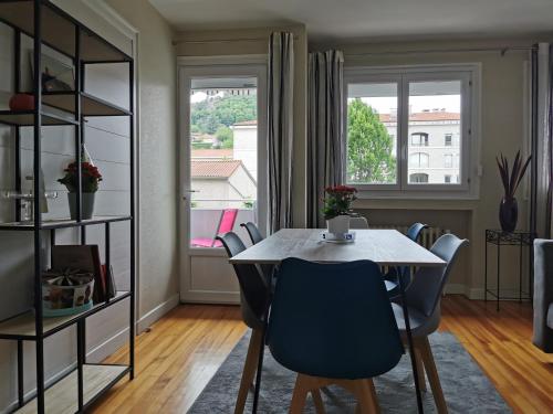 ein Esszimmer mit einem Tisch, Stühlen und einem Fenster in der Unterkunft Velay cocon appartement 4 chambres avec vue sur les monuments in Le Puy en Velay