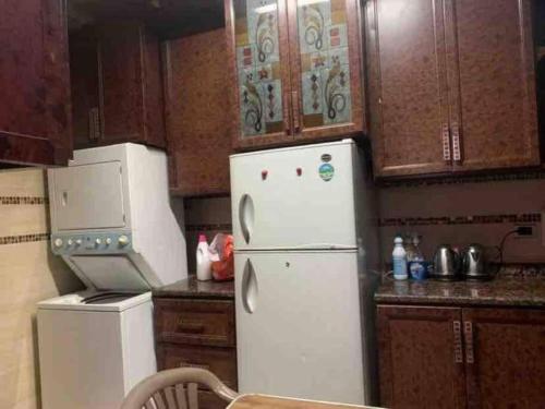 a kitchen with a white refrigerator and wooden cabinets at North coast sedra resort villa قريه سيدرا الساحل الشمالي in Alexandria