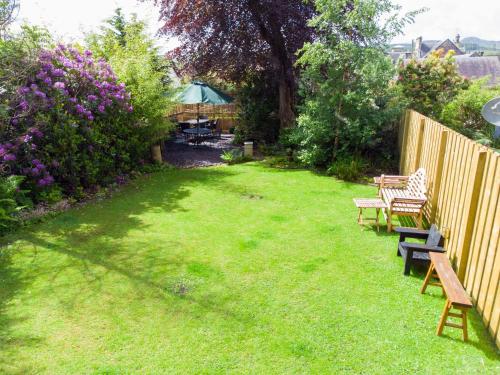 a yard with benches and a fence and flowers at Annfield House, Callander in Callander