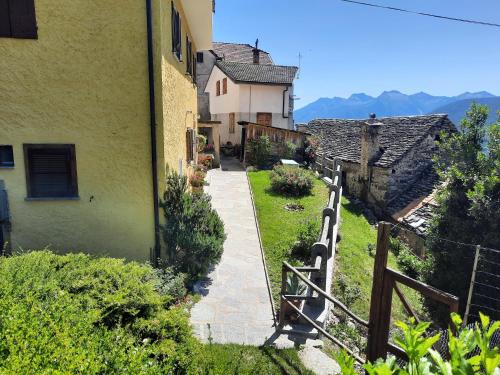 an outdoor walkway leading to a house with a fence at CasAmici in Bognanco