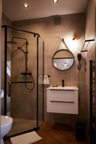 a bathroom with a shower and a sink and a mirror at Karczma Karnasów in Cisna