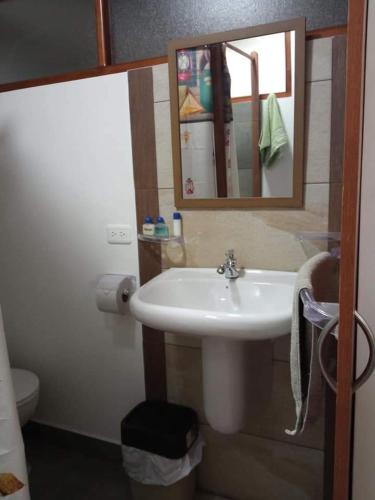 a bathroom with a sink and a mirror and a toilet at Hospedaje Wiruyana in Cotacachi