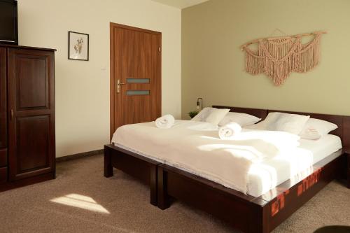 a bedroom with a large bed with white sheets at Karczma Karnasów in Cisna