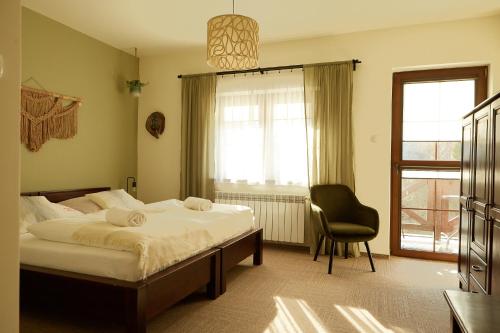 a bedroom with a bed and a chair and a window at Karczma Karnasów in Cisna