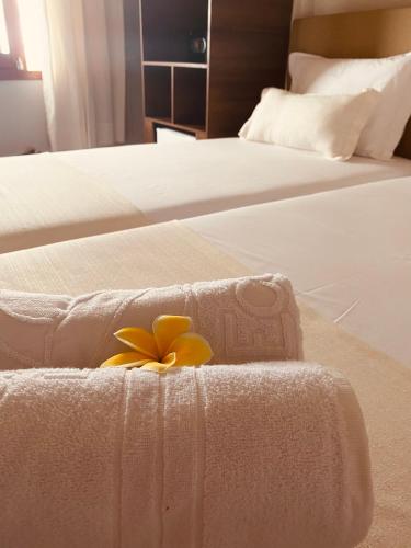 two beds with white sheets with a flower on them at Beach Eco Stays Hotel Boutique Lagoinha in Tigre