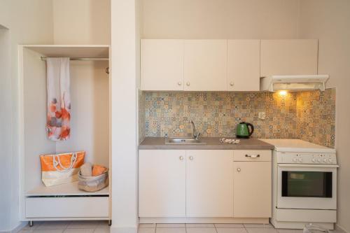 a kitchen with white cabinets and a sink at Minas Apartments in Divarata