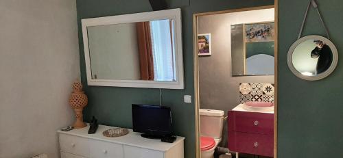 a bathroom with a television on a dresser and a mirror at le Mas d'Hubert in LʼIsle-sur-la-Sorgue