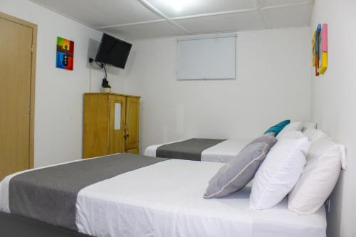 a bedroom with two beds and a tv on the wall at Hotel Poblado Suite in Barranquilla
