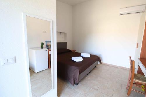 a bedroom with a bed with a mirror and a refrigerator at Agriturismo Monte Istulargiu in Valledoria