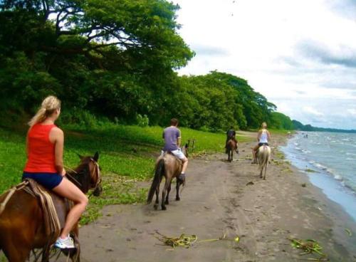a group of people riding horses on the beach at Hostel Santa Cruz Ometepe in Altagracia