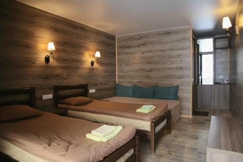two beds in a room with wooden walls at Kazbegi Cottages in Kazbegi