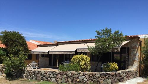 a house with a stone wall in front of it at Agriturismo Monte Istulargiu in Valledoria