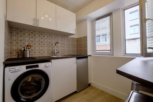 une cuisine avec une machine à laver et un évier dans l'établissement HONORÊ SUITE FERRANDIERE, à Lyon