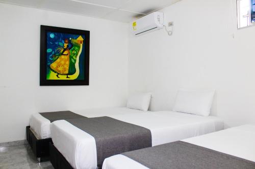 a room with two beds and a painting on the wall at Hotel Poblado Suite in Barranquilla