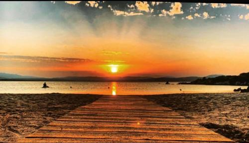 a wooden path leading to the beach at sunset at Villa Franci in Santa Teresa Gallura
