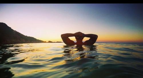 a man in the water with his hands on his face at Villa Franci in Santa Teresa Gallura
