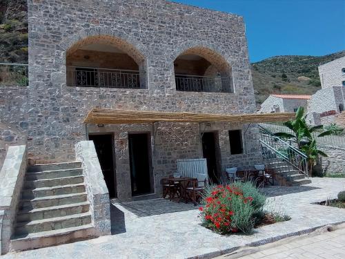 a stone house with stairs and a table and chairs at Mani Blue Studios in Oitylo