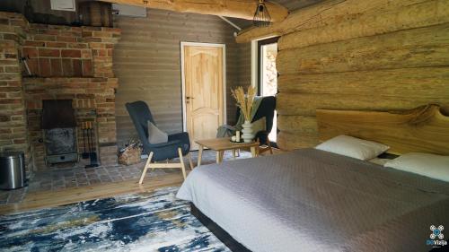 a bedroom with a bed and a fireplace and a brick wall at Gervės dvaro svečių namelis in Vėžionys