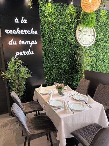 a white table with chairs and a clock on a wall at Parizs Garden Apartments in Debrecen