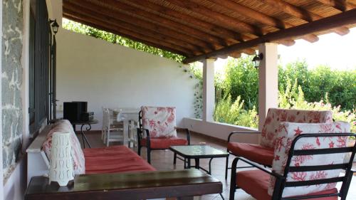um alpendre coberto com cadeiras, uma mesa e uma televisão em Countryside villa in Sardinia em Triei