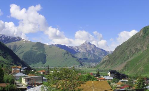 a village in a valley with mountains in the background at Milky Way in Stepantsminda