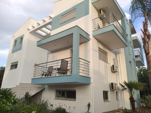a white building with blue balconies and palm trees at Armonia Studios Preveza in Preveza