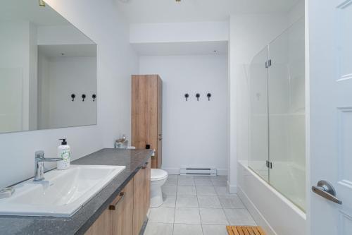 Baño blanco con lavabo y aseo en The Urban Oasis - Old Quebec - Gym - AC - Indoor Parking, en Quebec