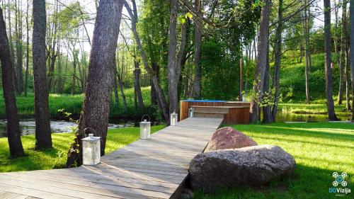 a wooden boardwalk in a park with a rock at Gervės dvaro svečių namelis in Vėžionys