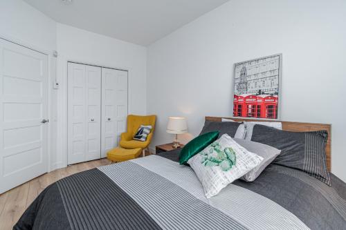 1 dormitorio con 1 cama y 1 silla amarilla en The Urban Oasis - Old Quebec - Gym - AC - Indoor Parking en Quebec
