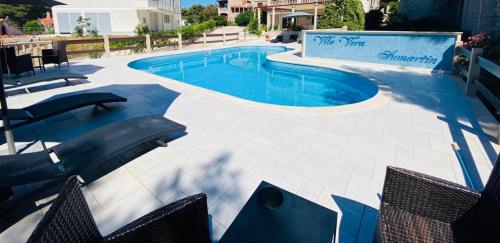 a swimming pool with chairs and a swimming pool at Vila Vera Seafront Apartments in Sumartin
