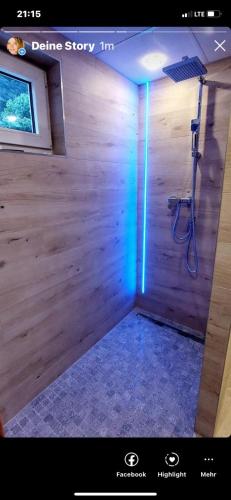 a shower with a blue light in a wooden wall at Waldhaus in Jáchymov