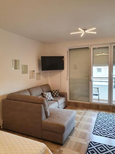 uma sala de estar com um sofá e uma televisão de ecrã plano em Apartman Bečići - Budva em Budva