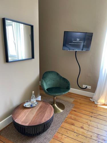 a living room with a green chair and a table at AUERSTEIN-Hotels auerstein & auerstein-mono in Heidelberg