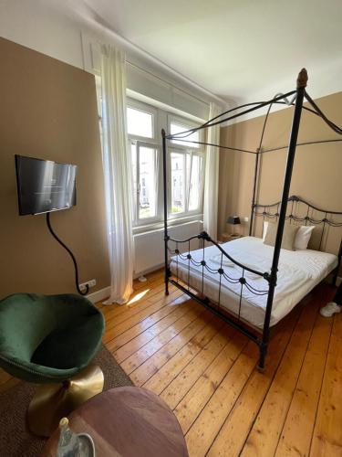 a bedroom with a four poster bed and a chair at AUERSTEIN-Hotels auerstein & auerstein-mono in Heidelberg