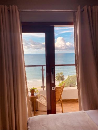 a bedroom with a view of the ocean from a balcony at Beach Eco Stays Hotel Boutique Lagoinha in Tigre