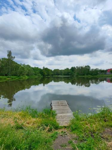 a lake with a wooden dock in the water at Leśniczówka in Rządza