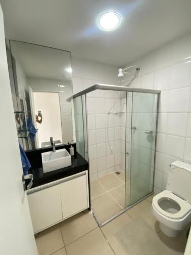 uma casa de banho com uma cabina de duche em vidro e um WC. em Flat a margem do açude velho em Campina Grande