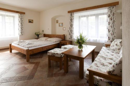 a bedroom with two beds and a table and a couch at Hezká chalupa in Strmilov