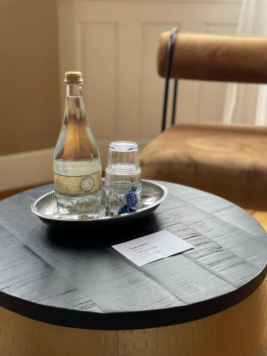 a bottle and a glass on a plate on a table at AUERSTEIN-Hotels auerstein & auerstein-mono in Heidelberg