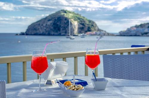two wine glasses sitting on a table with a view of the ocean at Hotel Regina del Mare in Ischia