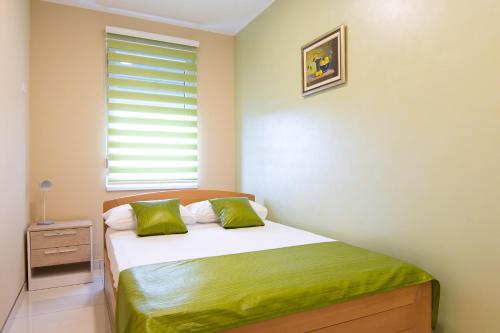 a bedroom with a bed with green sheets and a window at Jana apartmani in Novi Grad