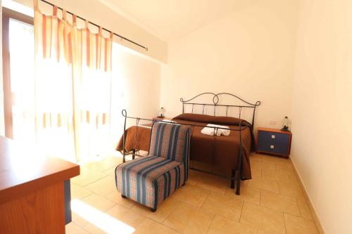 a bedroom with a bed and a chair at Agriturismo Monte Istulargiu in Valledoria